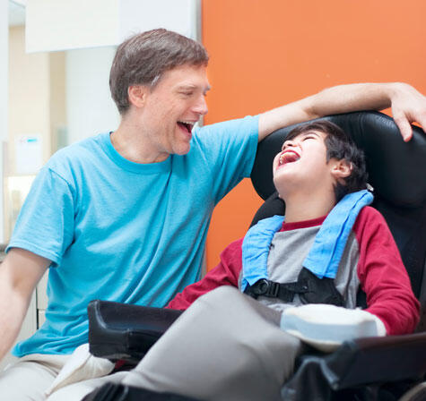 An adult and a child sat on a wheelchair, laughing together